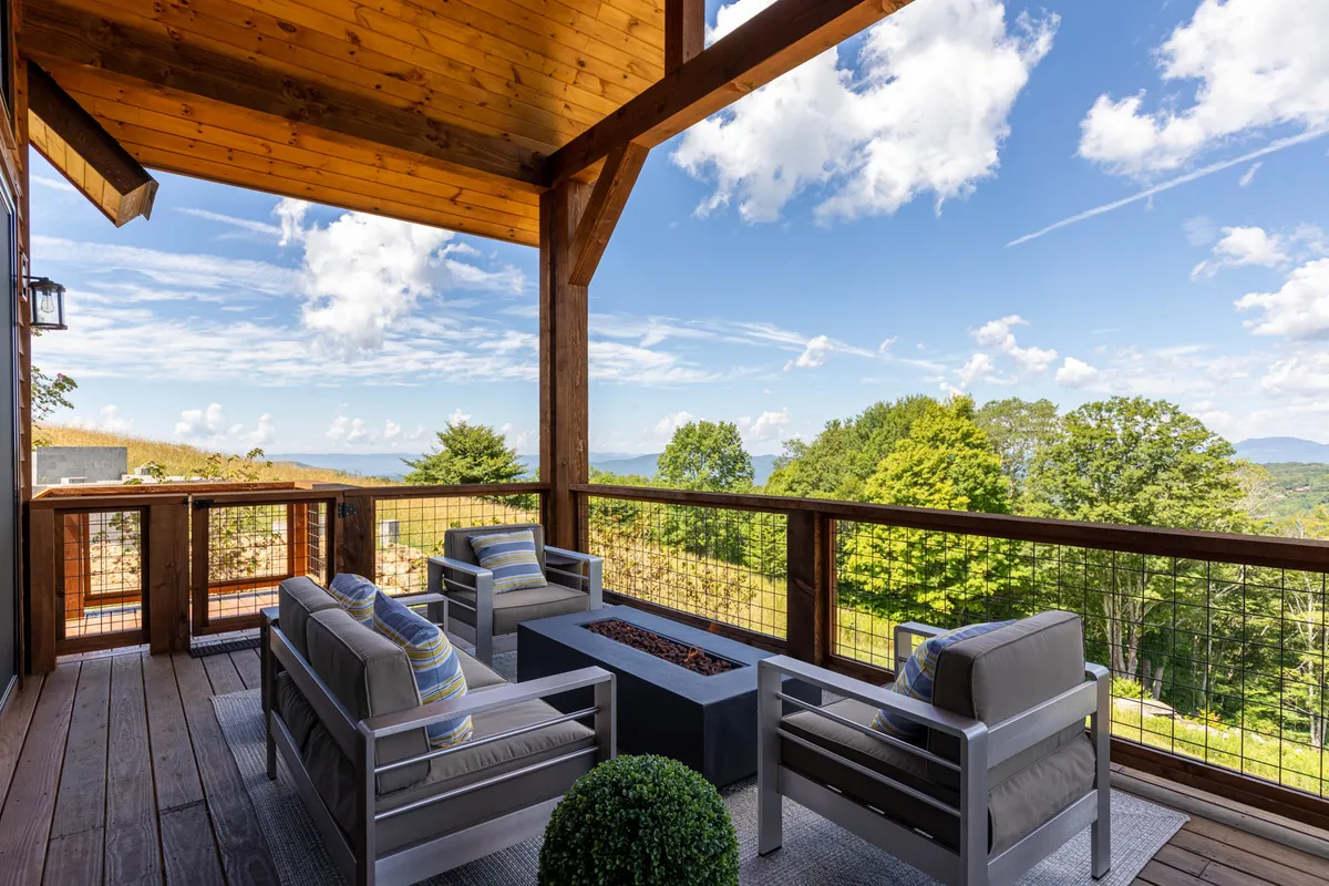 An inviting exterior seating area encircles a cozy fire pit, positioned to take advantage of sweeping natural vistas. Comfortable chairs invite guests to gather and connect as daylight fades or stars emerge overhead, creating an atmosphere ideal for socializing and storytelling.